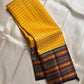 Marigold Mani Kattam – Pure Kanchipuram Silk Saree
Vibrant marigold yellow body with classic kattam checks
black borders with elephant & floral zari motifs
Rich black pallu adorned with green & zari stripes . Silk Mark Certified, delivery in 2 weeks