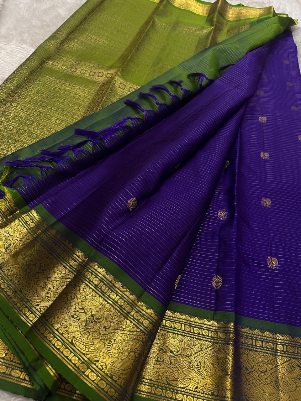 Hari Priya ✨ – Pure Kanchipuram Silk Saree
Royal Purple Body with Delicate Gold Zari stripes 
Emerald Green Korvai Contrast Border with Intricate Zari Weave
Grand Emerald Green Brocade Pallu with Traditional Motifs
Silk Mark Certified | Fall & Pico |
