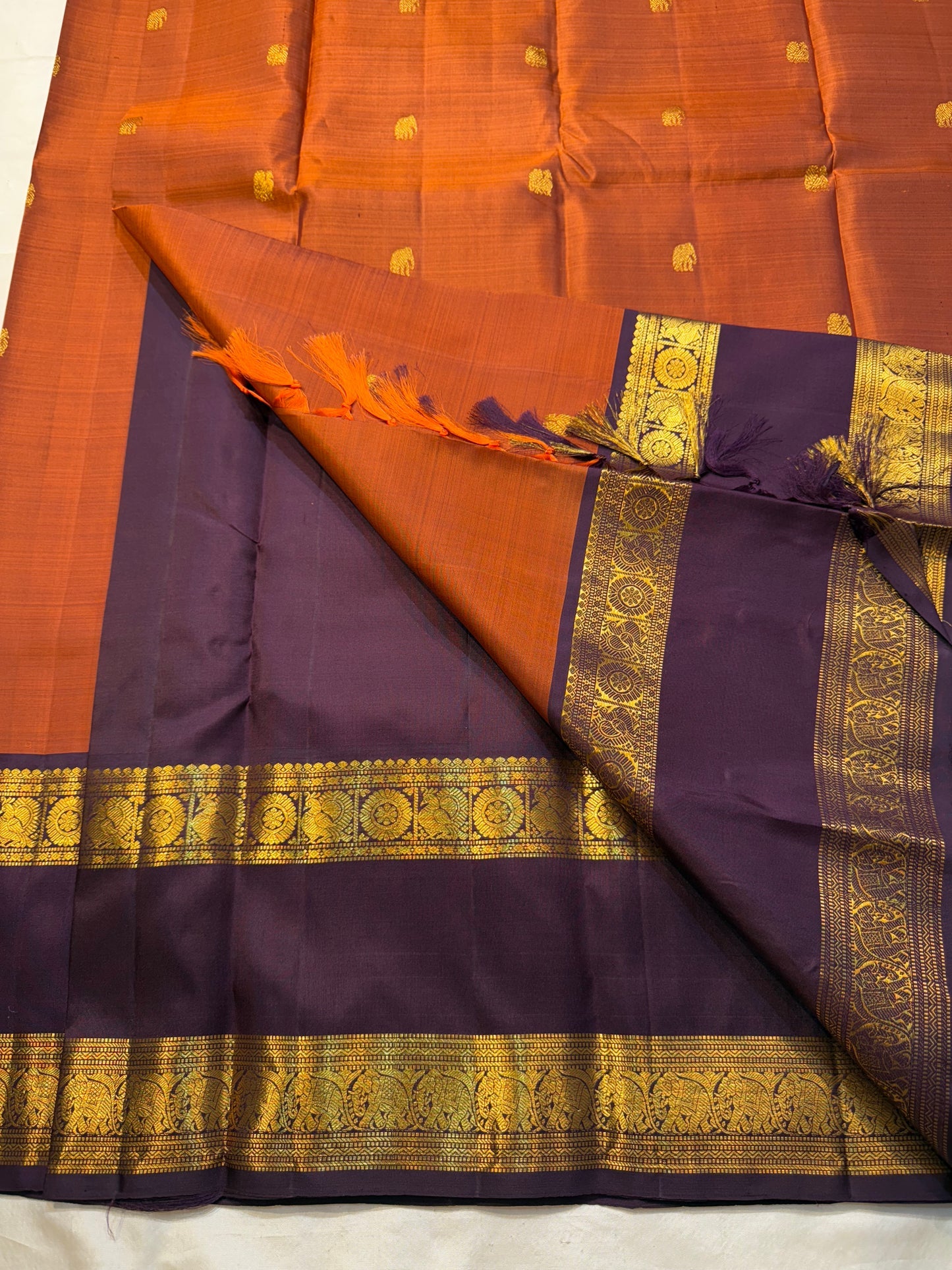 Poovizhi Rust Orange — Pure Kanchipuram Silk Saree
Deep aubergine body with rust-orange korvai borders & rich zari floral motifs
Silk Mark Certified • Blouse Stitching ($30) • Free Shipping within USA • Ships in Two Weeks