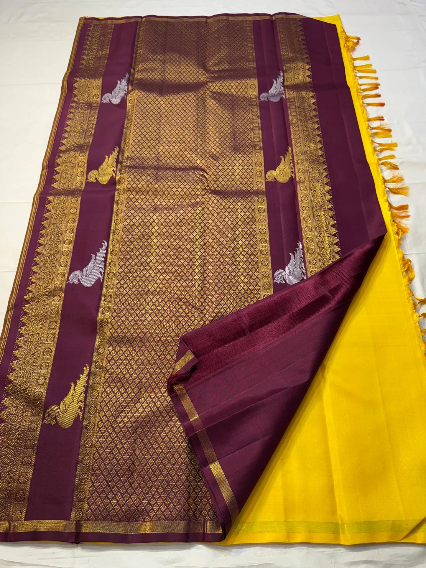 Kanaka Mayuri — Pure Silk Kanchipuram Saree
Haldi / Marigold Yellow with Silver-Zari Peacock Buttas ✨
Minimal Self Borders • Contrast Plum Brocade Pallu 💜
Handwoven in Pure Mulberry Silk | Silk Mark Certified ✅
Ships in Two Weeks Free | Idam Living