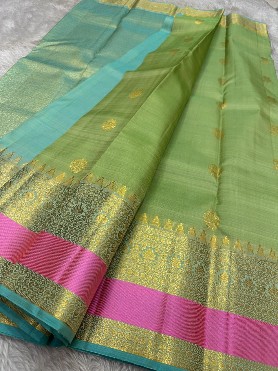 Rose pistachio meadow  – Pure Silk Kanchipuram Saree
Pista Green Body with Coin Paving Mayil Zari Buttas 🦚
Borders in Aqua & Rose with Pillayar Moggu Motifs ✨
Grand Aqua Pallu in All-Over Zari Brocade Weave
Silk Mark Certified | ships in 2 weeks