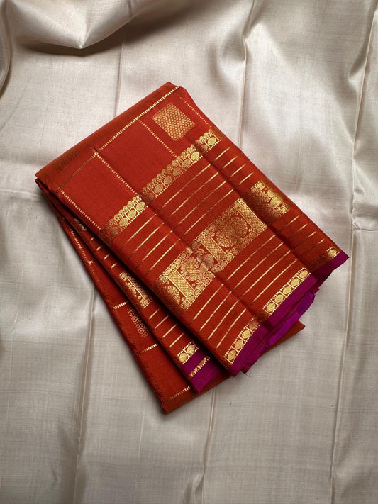 Pankajam 🌺 – Burnt Orange Kanchipuram Silk Saree with Zari Kattam, Dashed Lines, Kolam Motifs, Varisaipet Border with Thandavalam Zari Stripes, Rudrakshpet, Annam & Kamalam Motifs, Deep Magenta-Purple Selvedge & Ornate Pallu