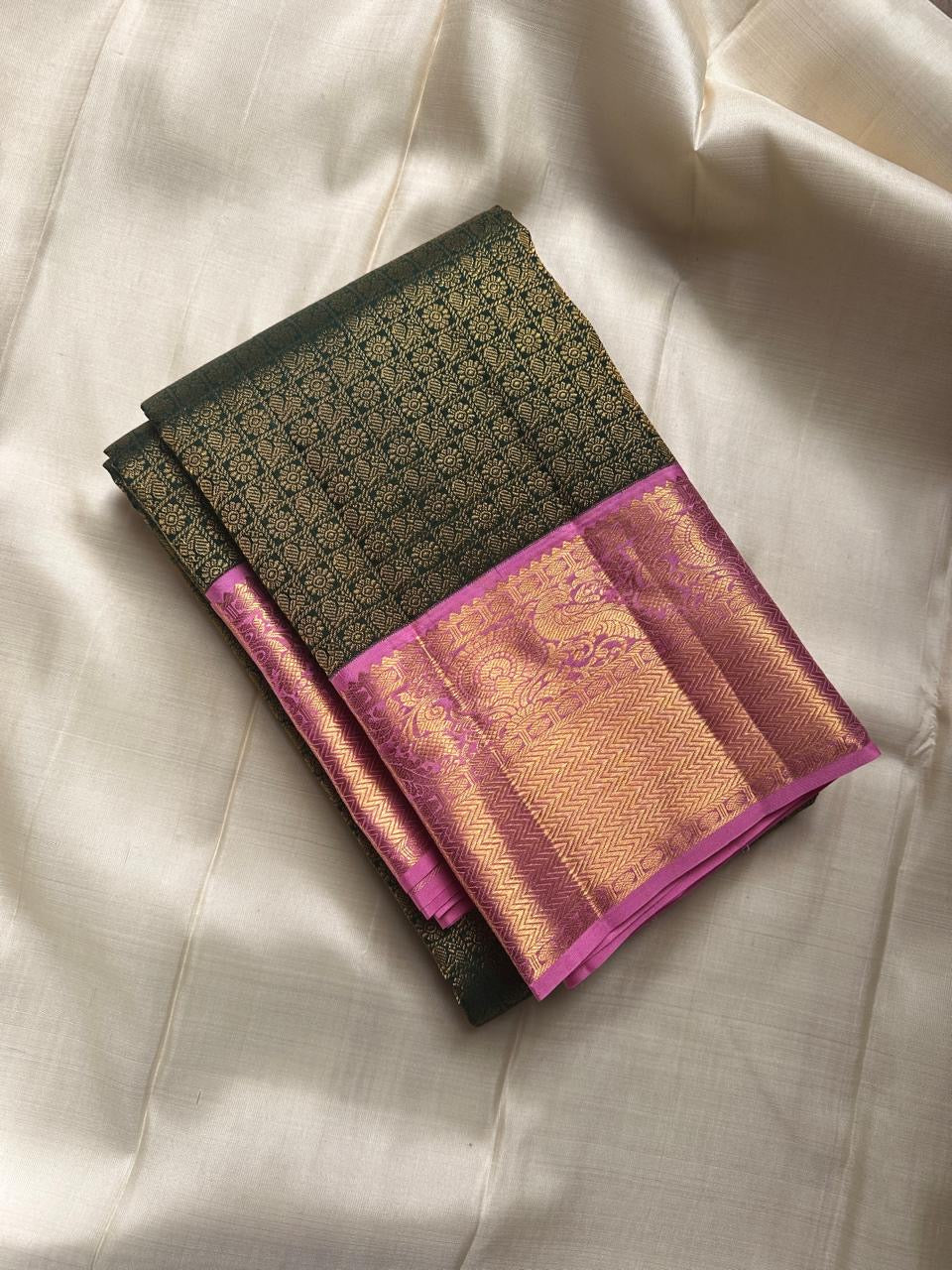 Iniya – Bottle Green & Pink Kanchipuram Pure Silk Saree with Floral Jaal and Mayil Border
Graceful and refreshing, Iniya is a handwoven masterpiece in bottle green with soft pastel pink accents. Delicate floral jaal and mayil motifs dance across the drape