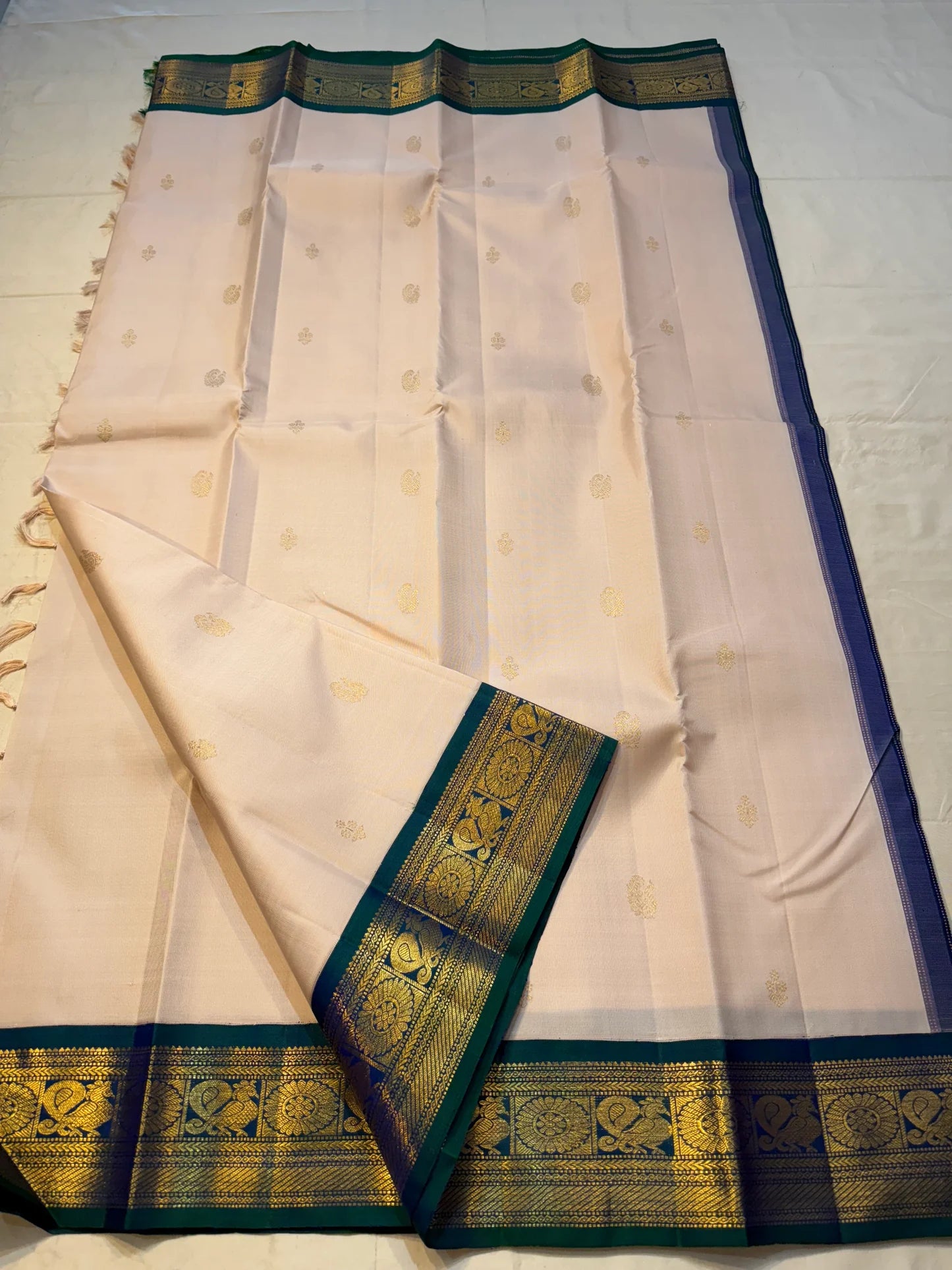 Mayilkazhuthu Shwetham — Pure Kanchipuram Silk Saree
Soft Ivory-Blush Body with Gold Zari Buttas & Peacock Blue-Green Border
Silk Mark Certified • Free Shipping within USA • Ships in Two Weeks