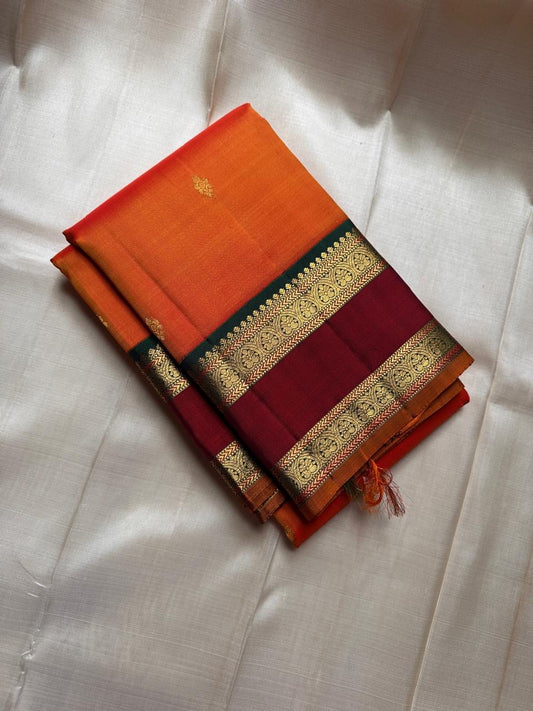 Orange Maragatha Korvai — Kanchipuram Pure Silk

Sunset aruna-orange body with delicate single zari butta

Deep maroon korvai borders with floral rosette motifs; green selvedge

Rich maragatha-green zari pallu (zari jaal & vine panels)..description