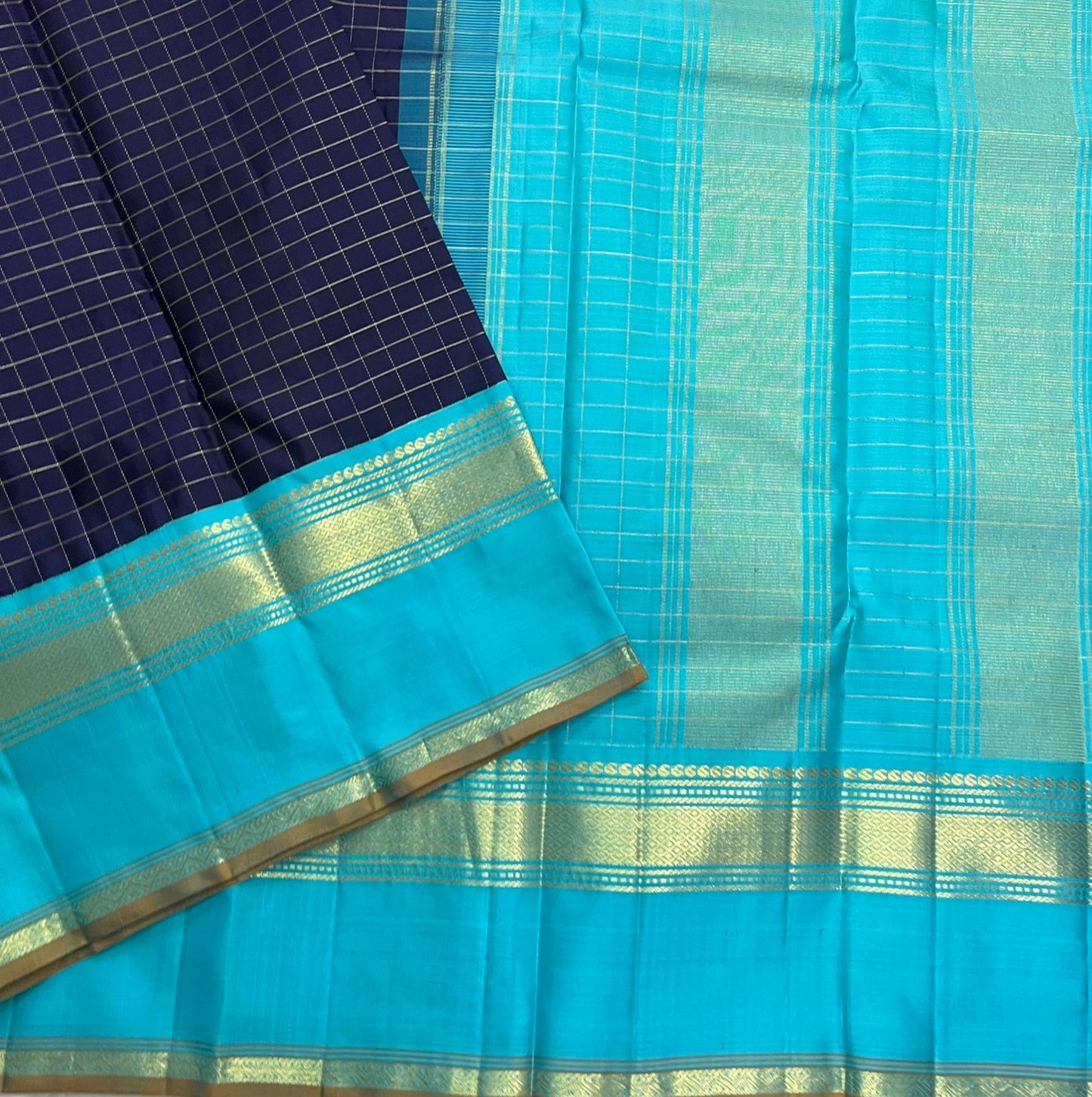 Indigo Teal Kattam – Pure Silk Kanchipuram Saree
Deep Indigo Body with zari Kattam Checks
Teal Contrast Korvai Border with maanga pet and mayil kann border, maanthulir selvedge  , silk mark certified -ships in two weeks