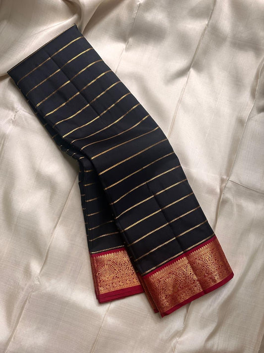 Black with Gold zari stripes , thandavalam stripes run across the body like rays of light. Framed with a bold red border