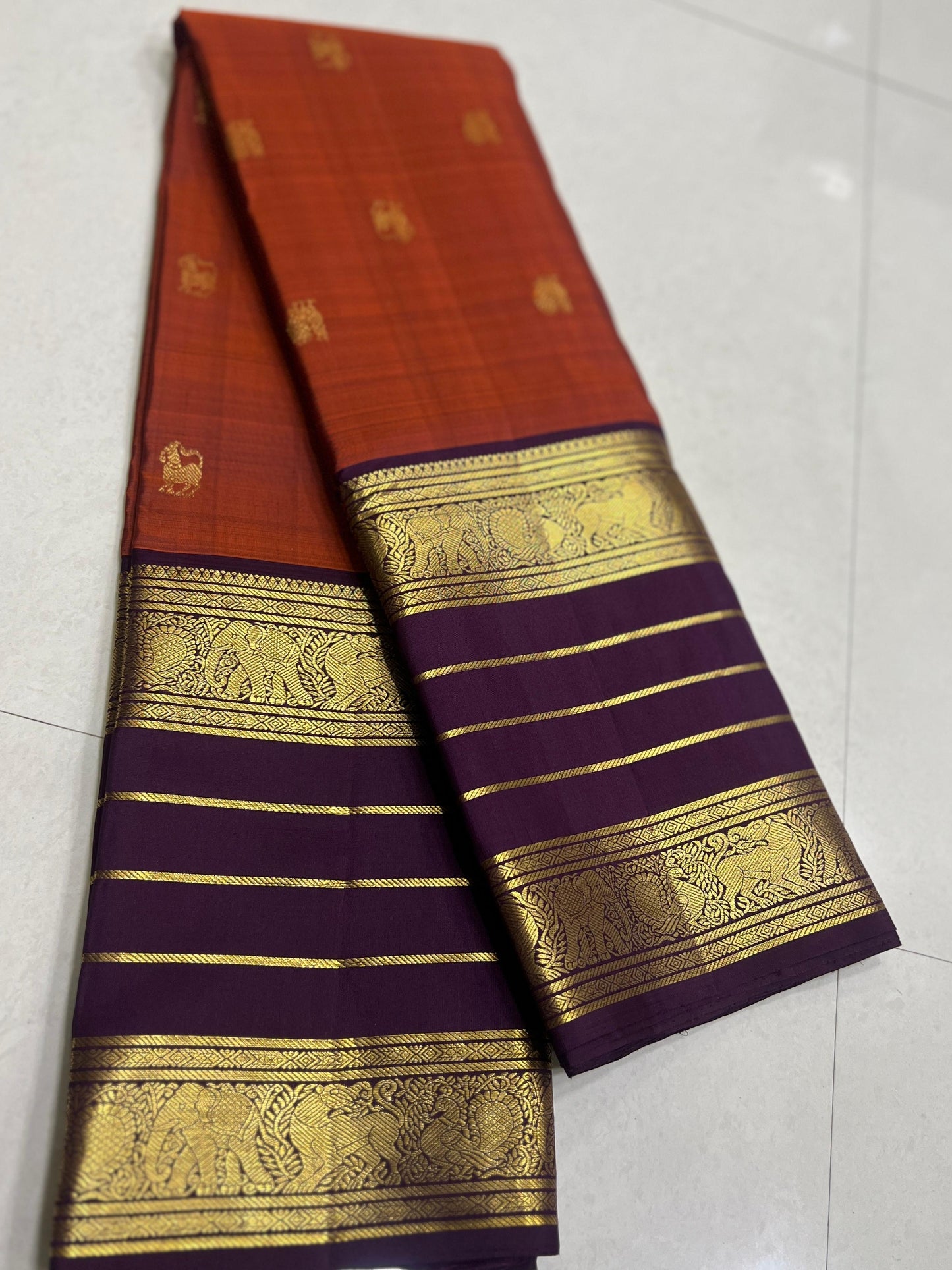 Karpagam – Burnt Orange & Coffee Elegance ✨🪔
A glowing burnt orange body adorned with gold zari peacocks 🦚 and mythical Yazhi 🐉 motifs. The deep coffee border shimmers with Varisaipet geometric zari, while the grand pallu unfolds in panels of Vanasring