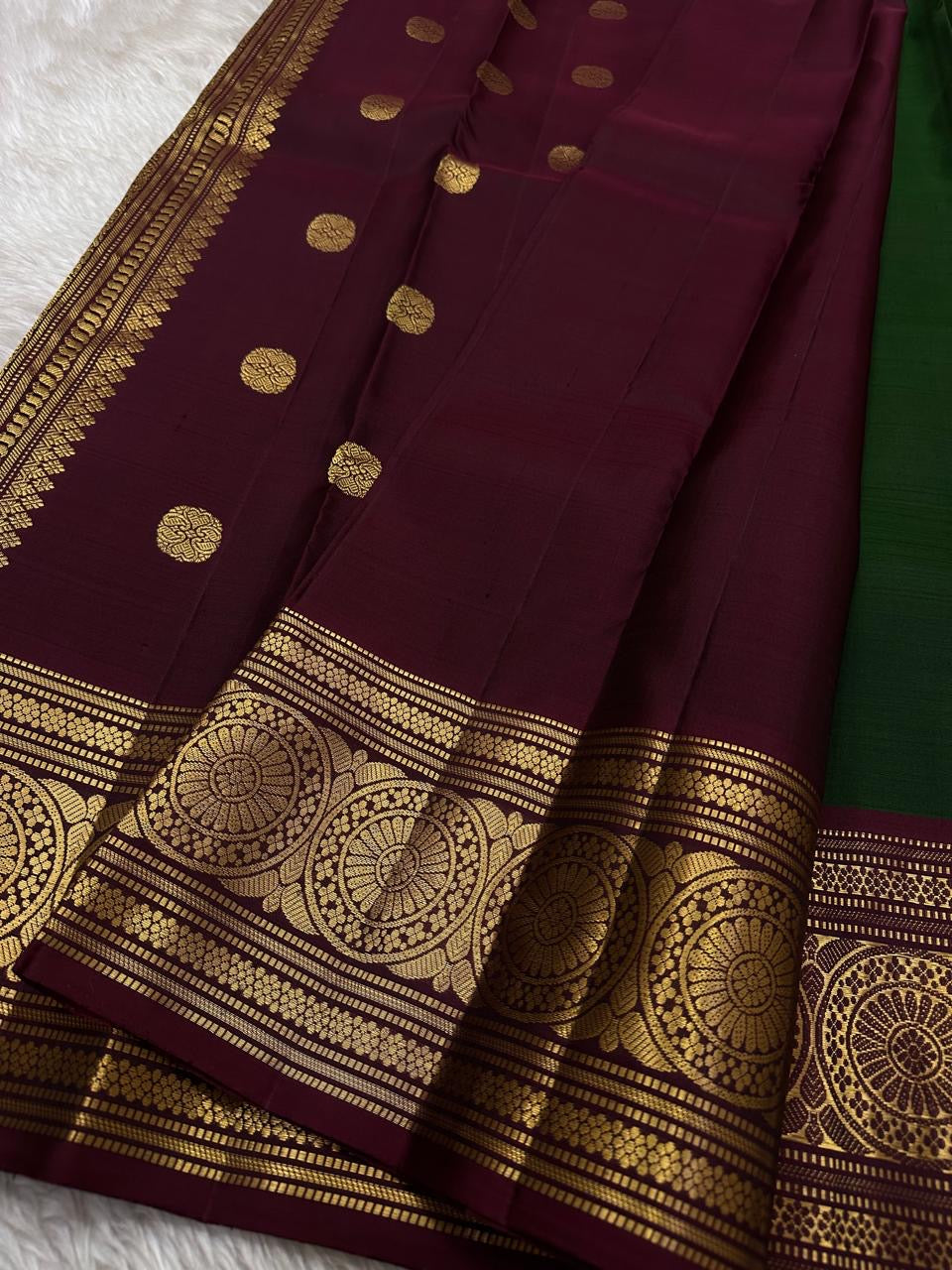 Pachai Butta – Pure Kanchipuram Silk Saree
Emerald silk scattered with radiant buttas.
A wine korvai border rich in gaja artistry.
Floral medallions glow in antique-gold zari.

Silk Mark Certified, delivery in 2 weeks