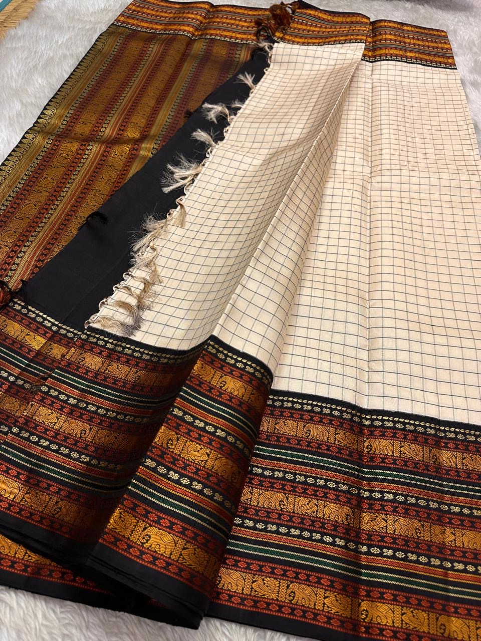 Ivory Varisaipet – Pure Kanchipuram Silk Saree
Pattunool Kattam Checks on Ivory Base
Black Borders with Elephant & Floral Motifs
Antique Gold, Rust & Bottle-Green Stripes

Silk Mark Certified, delivery in 2 weeks