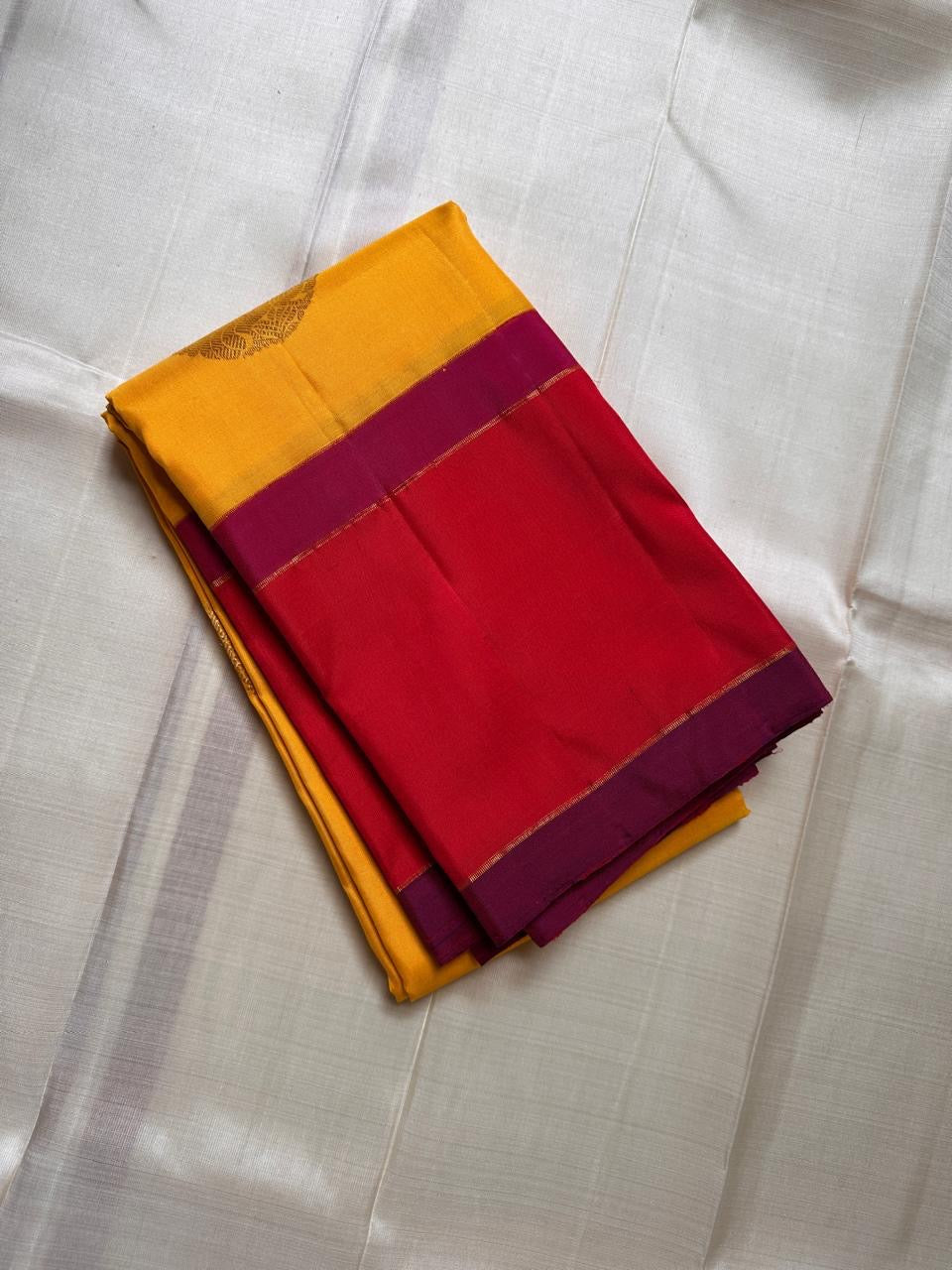 Mustard yellow silk saree fold with zari woven coin buttas and magenta border