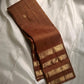 vasantham  Brown– Handwoven Kanchipuram Silk Saree A poem in Brown silk. The body glows in a serene earthy Brown, softly accented by delicate gold vertical lines and dainty gold zari buttas that glint like little blessings.