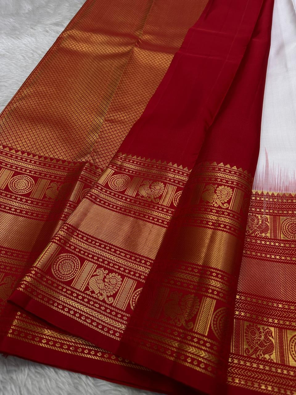 A true festival essential white with dashing red pure silk Kanchipuram saree with a kamalam and mayil detailed border zari work , red reku and Pallu