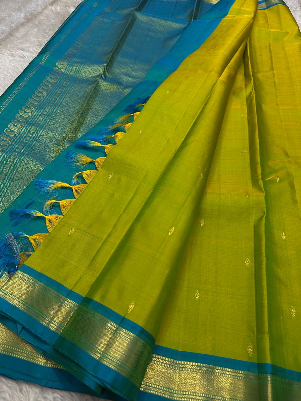 Citrus and Teal – Pure Kanchipuram Silk Saree
Dual-tone body in parrot green and turmeric.
Elegant gold leaf buttas across the drape.
Teal korvai border
Rich teal pallu with diamond jaal and temple motifs.

Silk Mark Certified, delivery in 2 weeks