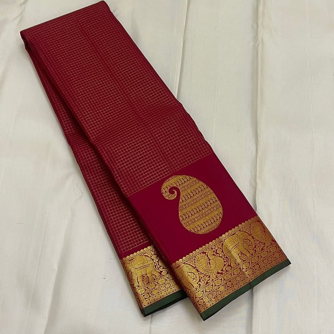 Ushas, Deep Arakku Red Pure Kanchipuram Silk Saree
Radiant Oosi Kattam body with ornate Paisley 2gm Zari
Vanasringaram,Muthuseer,Kamalam border with Fishpettu detailing
Exquisite diamond-pet grid Zari pallu, richly finished with a bold deep green selvedge