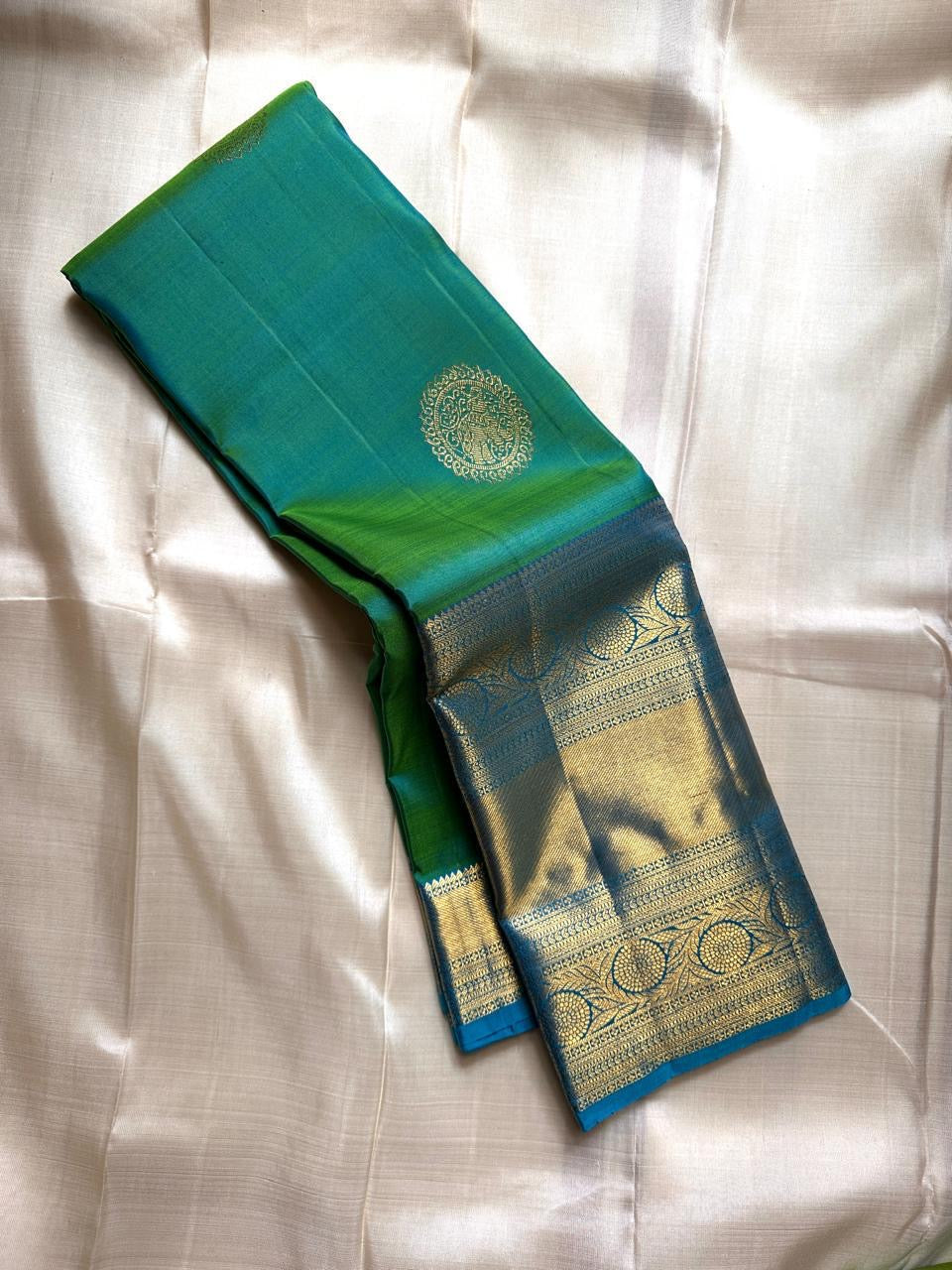 Parrot green silk saree with zari medallion butta and sky blue border, folded display