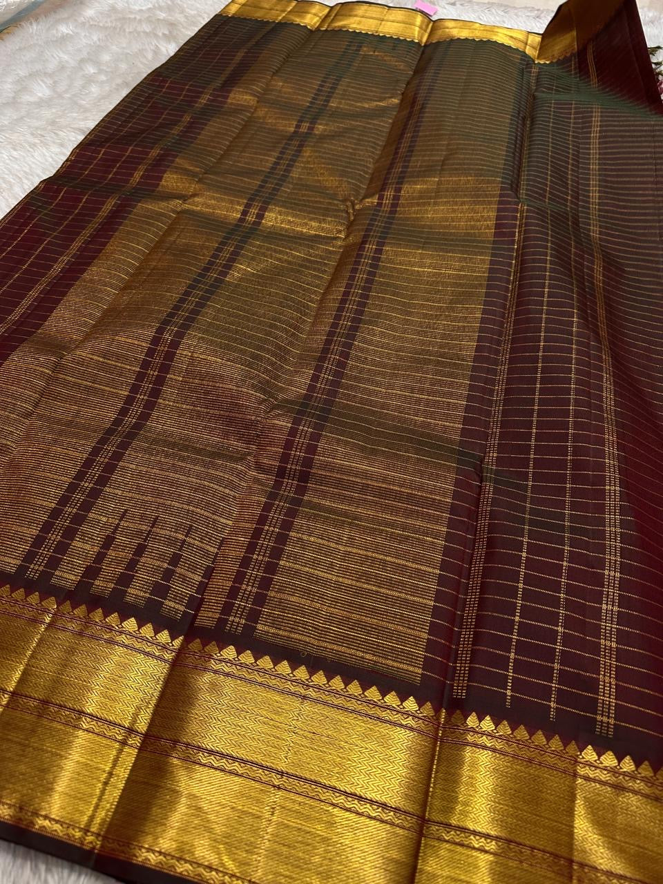 Ruby Zari Kattam – Pure Kanchipuram Silk Saree
Rich Ruby Red Body with Gold Zari Checks
Broad Golden Border with Maroon Highlights & Temple Motifs
Dual-Toned Maroon-Green Pallu with Intricate Zari Weaves

Silk Mark Certified, delivery in 2 weeks