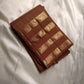 vasantham  Brown– Handwoven Kanchipuram Silk Saree A poem in Brown silk. The body glows in a serene earthy Brown, softly accented by delicate gold vertical lines and dainty gold zari buttas that glint like little blessings.