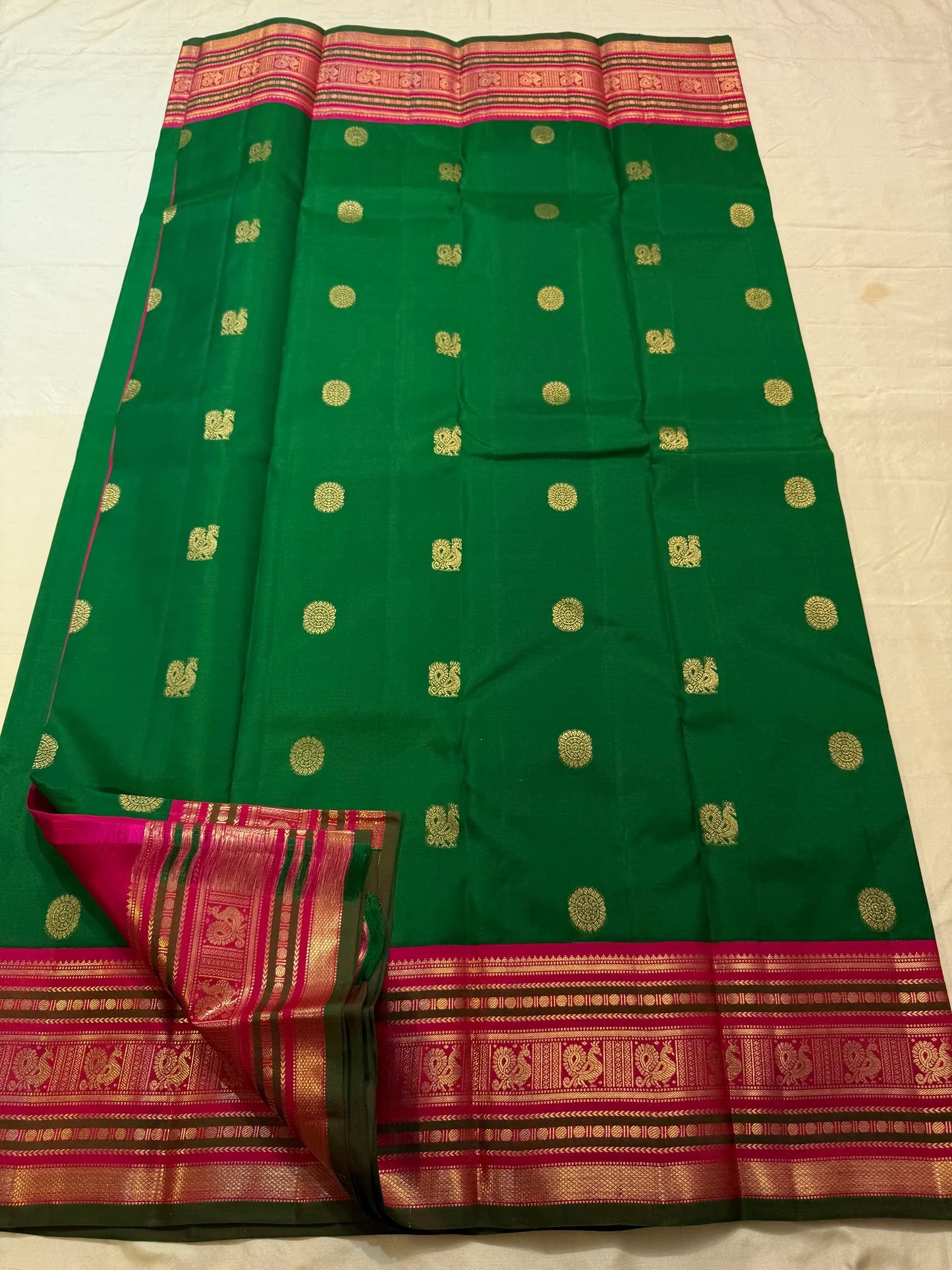 Emerald green and magenta Kanchipuram Varisaipet saree folded flat — full length view