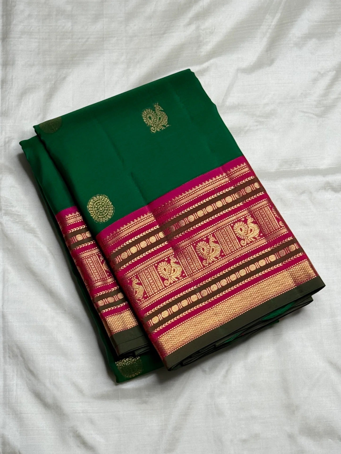 Deep emerald green Kanchipuram saree body with scattered Kamalam and Kili butta in gold zari — close-up