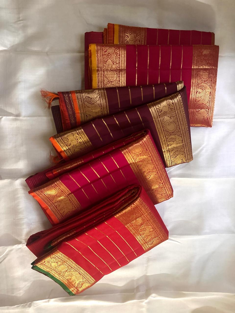 Red sarees with gold and orange patterns on a white background