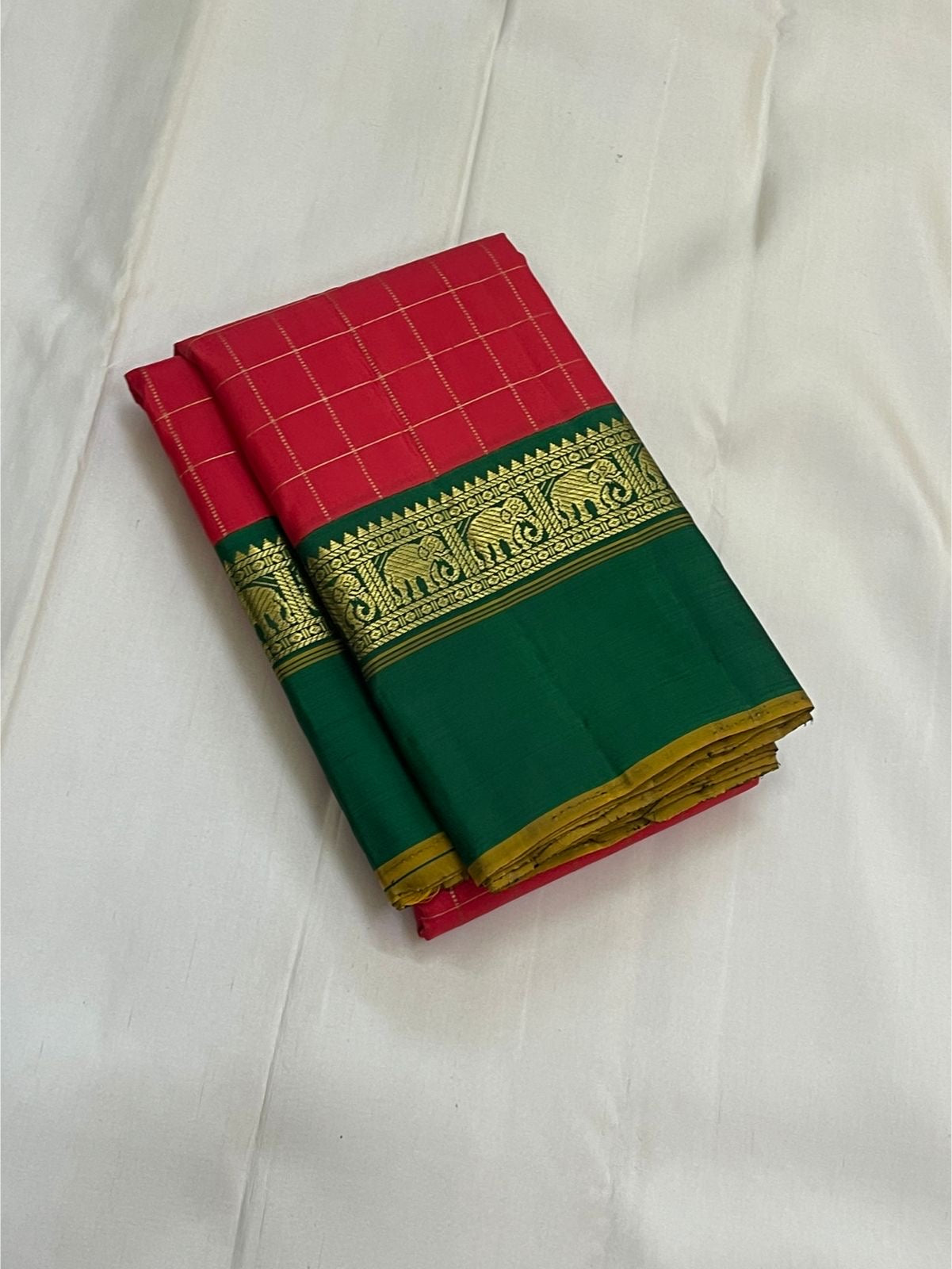 Emerald Ruby Korvai
Pure Kanchipuram Silk Saree – Ruby Red Body with muthu kattam  Grid Checks
Emerald Green Korvai Borders Adorned with Zari Elephant Motifs
Grand Green Zari seer Pallu with Traditional motifs 
Silk mark certified, ships in 2 weeks