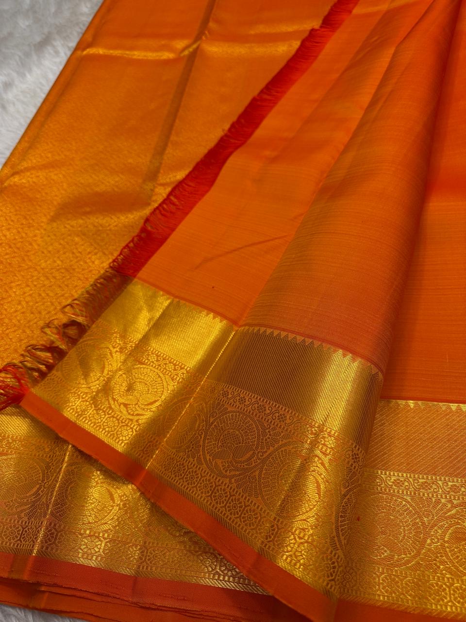 Agnika – orange Kanchipuram Silk Saree with Mayil Chakram Butta & Orange Border Fiery and regal, Agnika is a pure Kanchipuram silk saree featuring a rich red body adorned with intricate Mayil Chakram buttas.