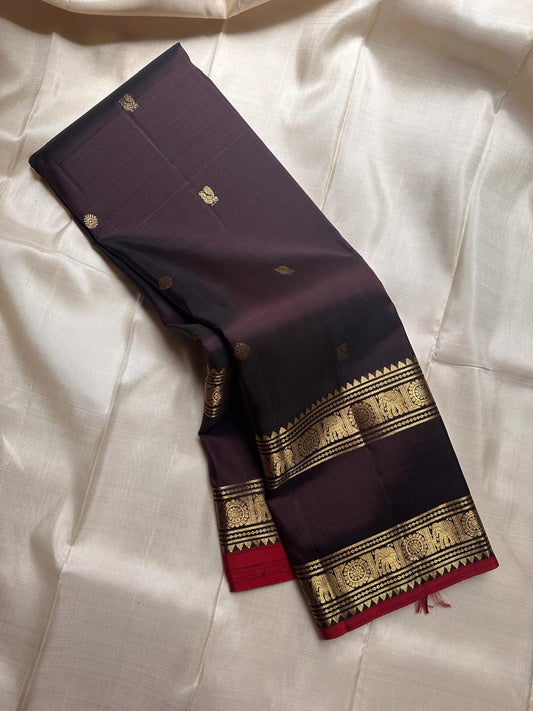 A rare Shot of vermillion and black, shimmers like molten dusk. Rettapet border mayil chakram butta pure silk Kanchipuram saree