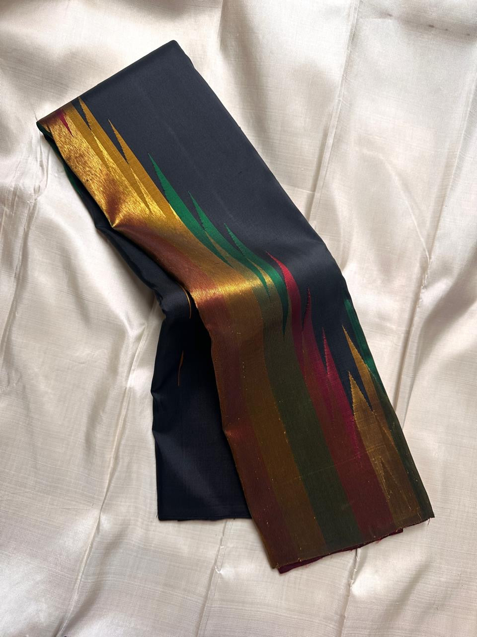 Folded black Ettukol weave Kanchipuram silk saree with multicolor flame-like zari pattern