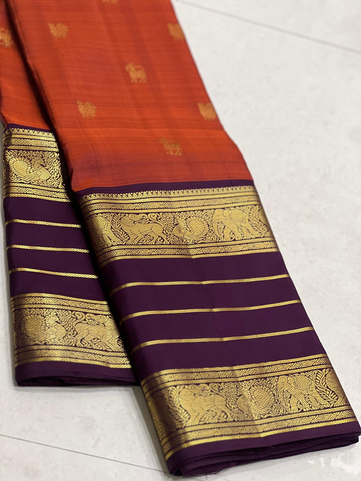 Karpagam – Burnt Orange & Coffee Elegance ✨🪔
A glowing burnt orange body adorned with gold zari peacocks 🦚 and mythical Yazhi 🐉 motifs. The deep coffee border shimmers with Varisaipet geometric zari, while the grand pallu unfolds in panels of Vanasring
