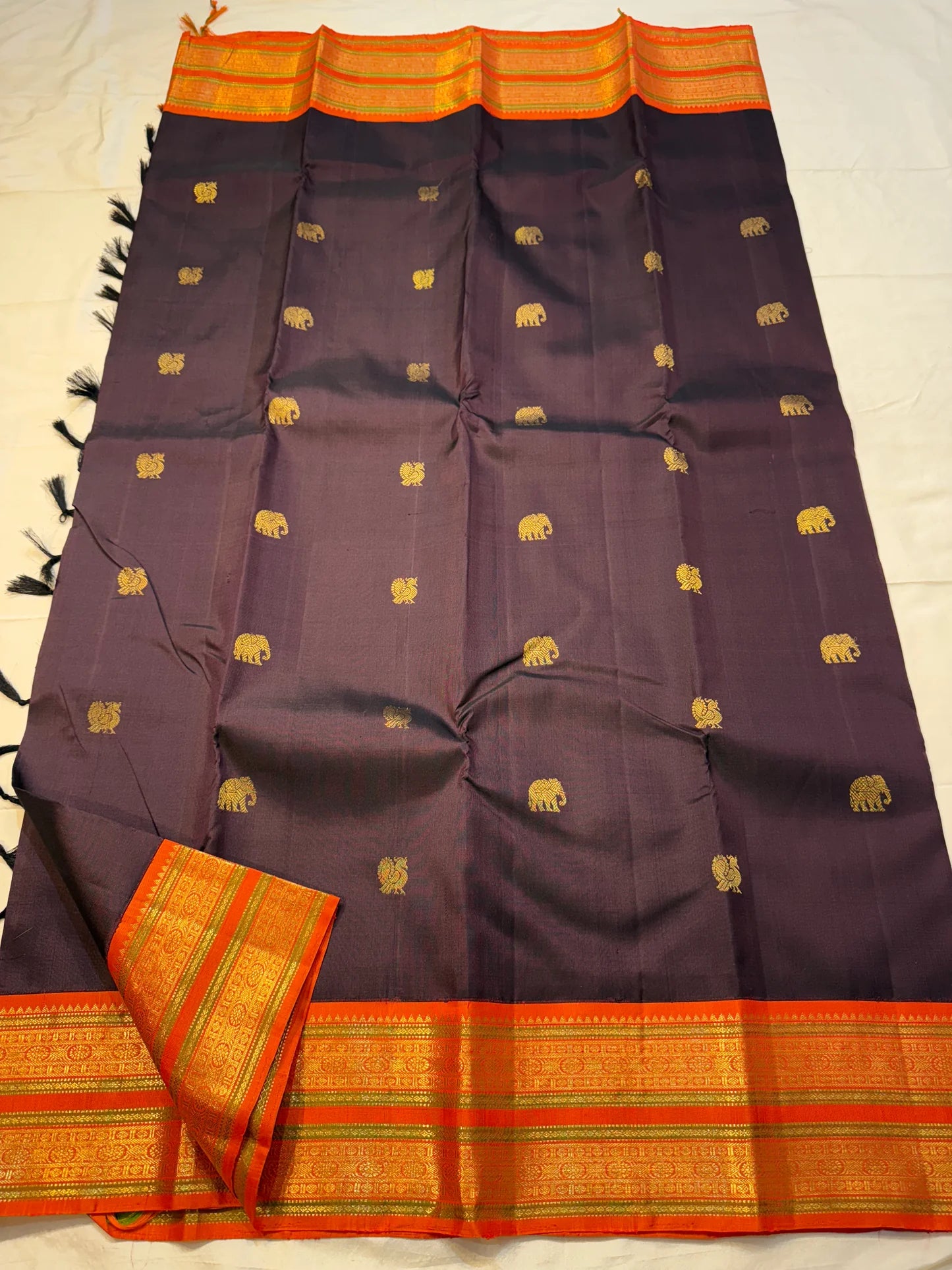 Deep Cocoa Manjari — Pure Kanchipuram Silk Saree
Rich cocoa-aubergine body with antique-gold manjari buttas, paired with a radiant kavi-orange korvai border and green selvedge accent.
Silk Mark Certified • Blouse Stitching Available ($30) • Free Shipping