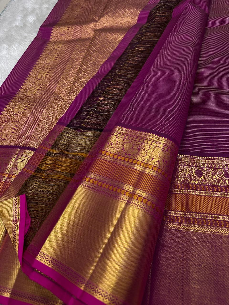 Close-up of magenta Kanchipuram saree pallu with dense gold zari weaving and peacock motifs