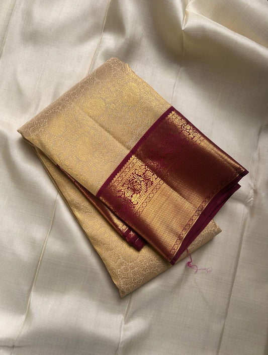 Ragini – Ivory & Gold Kanchipuram Pure Silk Saree with Floral Jaal & Maroon Baavanji Border
Timeless elegance shines through the delicate ivory base and shimmering gold zari floral jaal. The rich maroon Baavanji border and intricate pallu details complete