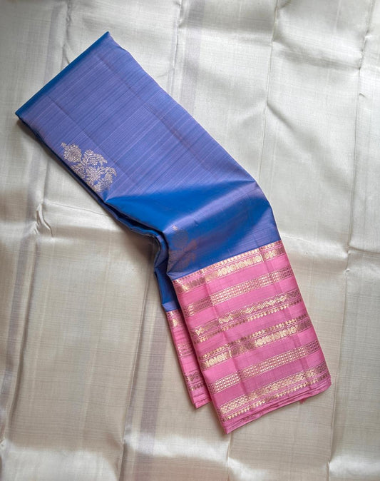 Ramyam, meaning pleasant and delightful, features a mesmerizing blue–purple shot body that shimmers with every movement. Its radiant pink korvai border and pallu, adorned with traditional Varisaipet zari stripes, add festive brilliance.silk mark certified