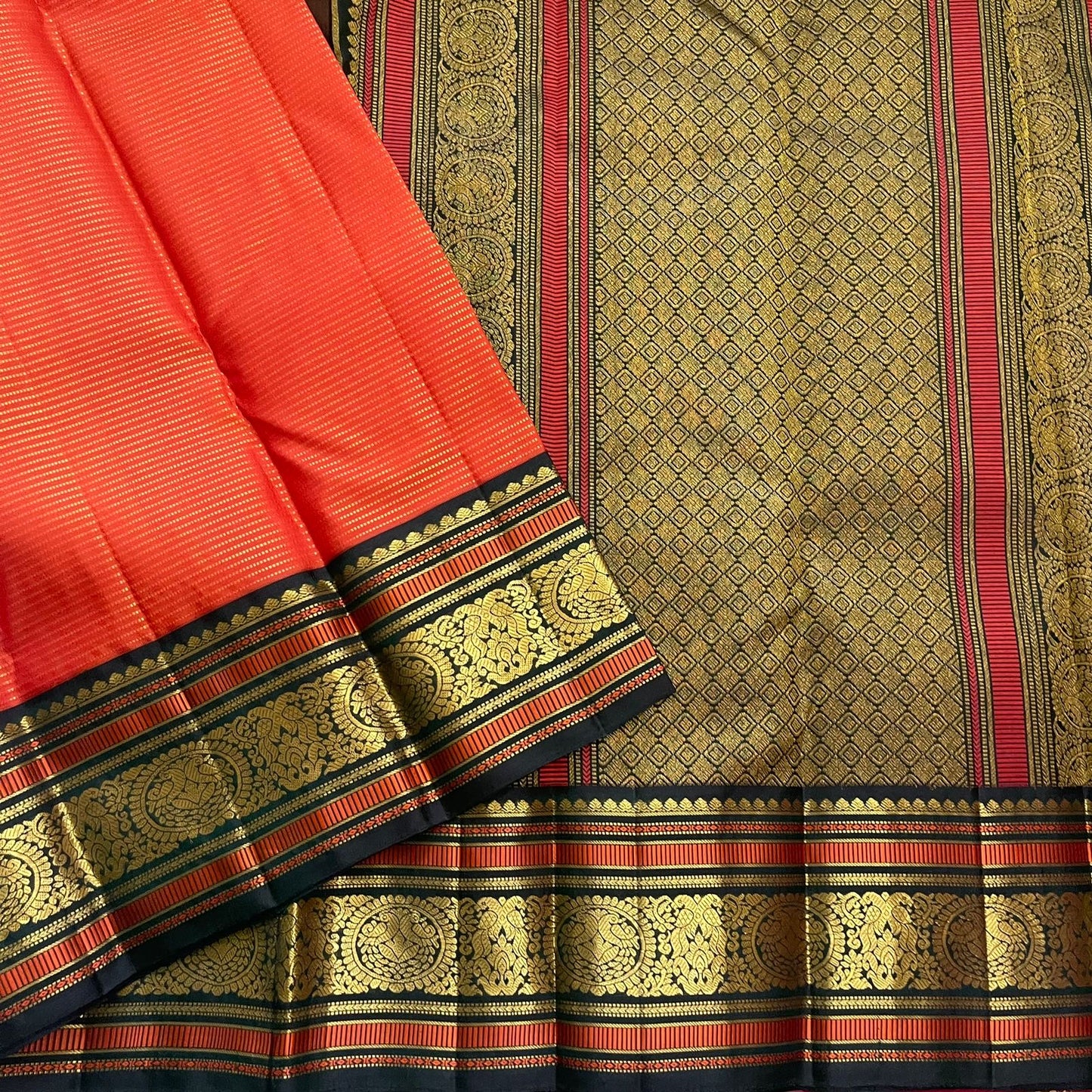 Aruna Mayil Chakram
Pure Kanchipuram Silk Saree – Reddish-Orange Body with Gold Zari Chakram Buttas
Contrast Bottle Green Korvai Borders with Mayil & Temple Motifs
Grand Zari Pallu with Diamond Brocade Weave & Hand-Knotted Tassels
Silk Mark Certified ✅ |
