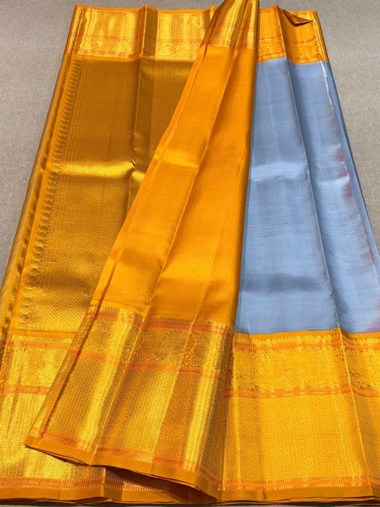 Eesha – Grey-Blue & Mustard Kanchipuram Pure Silk Saree.
Zari Butta All Over with Hamsa / Annapakshi   Motifs in Arai Maadam border . 
Detailed Chevron in pure 3g Zari Pallu with Muthu Seer Border for a Timeless Drape