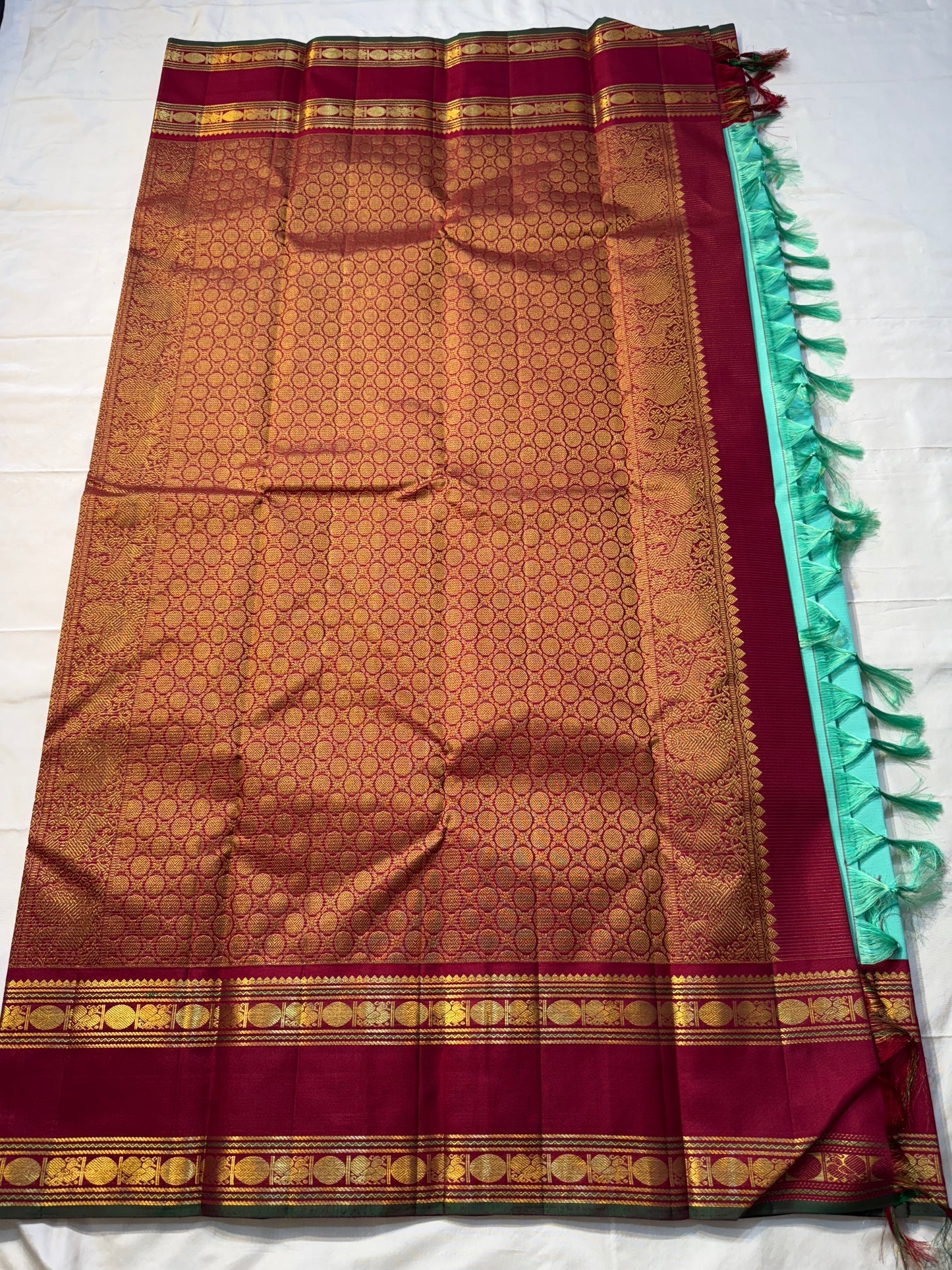 Neer Pachai Vairaoosi — Kanchipuram Pure Silk saree 

Sea-foam/aqua body with classic Vairaoosi pinstripes

Contrast ruby-maroon korvai borders with gold chakram & floral panels

Grand maroon pallu with all-over chakram jaal and paisley vines; aqua tassel