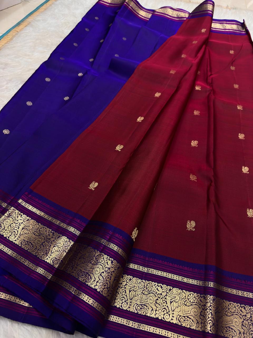 Folded deep arakku / pomegranate-crimson red body handwoven pure silk Kanchipuram saree, product 10, photographed on a pale neutral fabric background