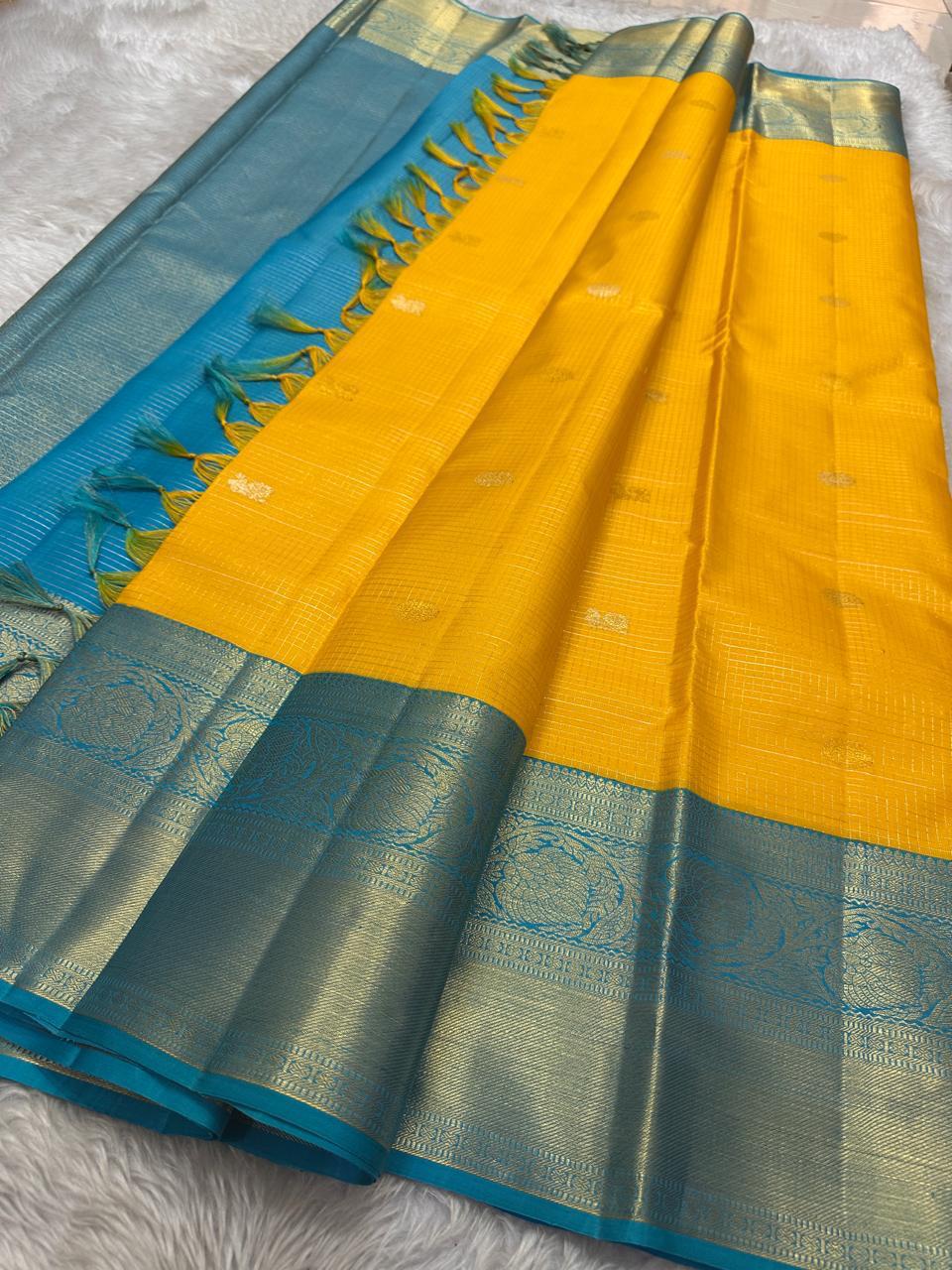 This radiant yellow pure silk drape is elevated by an exquisite and unexpected pairing — a serene sky blue border, making it both eye-catching and rare. Fine zari checks shimmer gently across the body, timeless bavaanji border