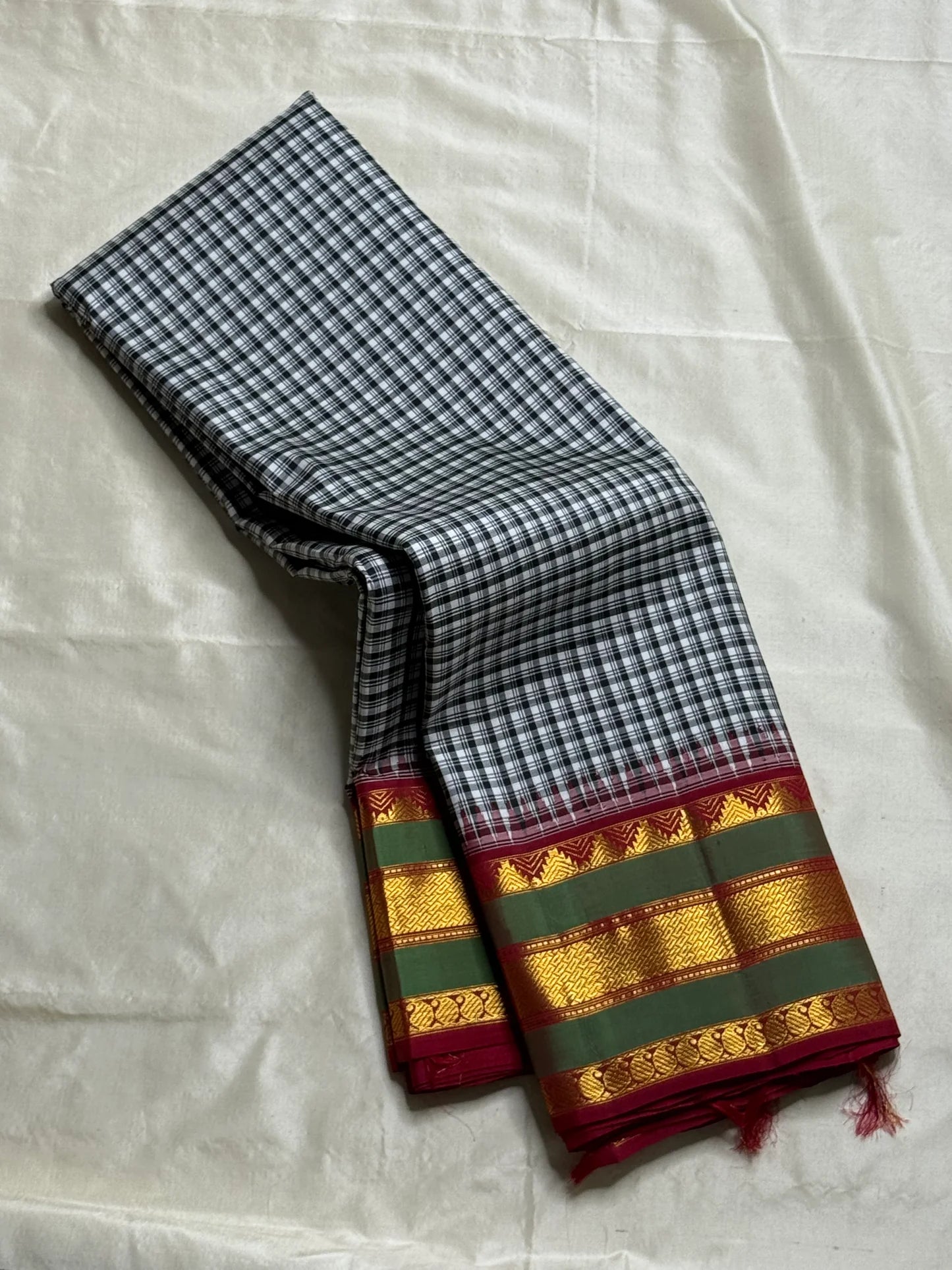 Onyx Plaid – Pure Kanchipuram Silk Saree
Black & Ivory Micro-Checks Body (Kattam) ✨
Parrot-Green Korvai Border with Gold Zari
Crimson Pallu with Orange Panel & Kaddi Stripes

Silk Mark Certified, delivery in 2 weeks