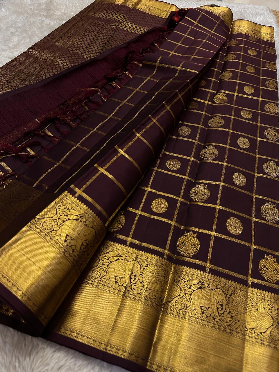 Full pallu view of plum Kanchipuram silk saree with dense gold zari weaving and bold elephant motif border.