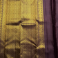 Tanaya features a regal mulberry mauve purple body adorned with golden kamalam and mayil buttas. Its elegant dual-tone border—coffee brown on top and emerald green below with rich temple-inspired zari work with medallions and florals woven, rich Pallu.