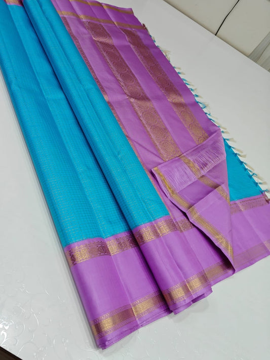 Azure Kattam – Pure Silk Kanchipuram Saree
Aqua Body with Mini Checks (oosi zari  Kattam) ✨
Lilac Contrast Border in Zari Weave
Elegant Pallu with Traditional Zari Panels
Silk Mark Certified ships within  2 weeks