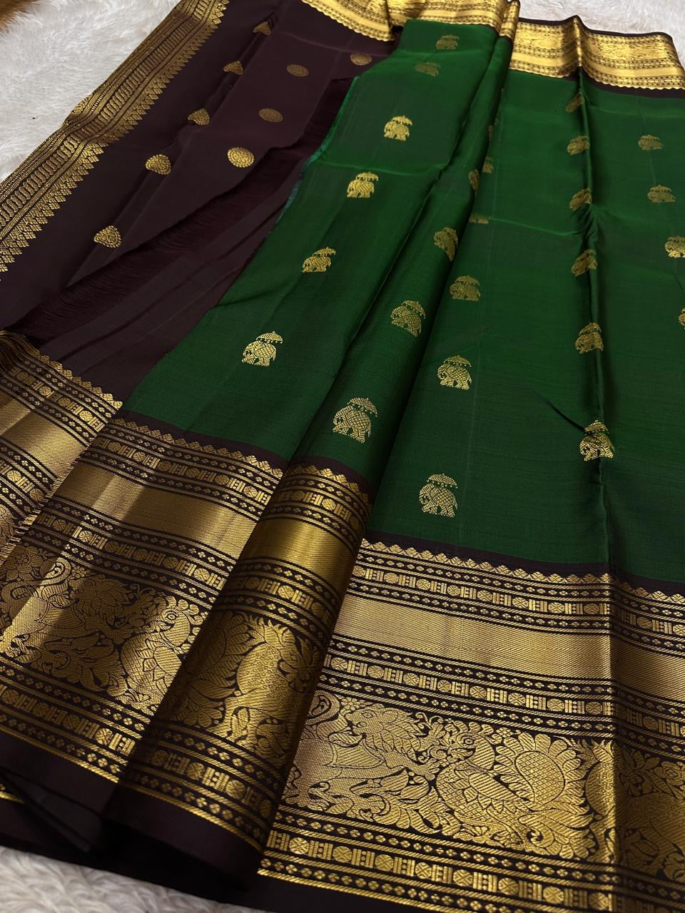Emerald Green Elephant Butta — Pure Kanchipuram Silk Saree
Emerald green body with antique-gold zari elephant buttas and grand coffee-brown korvai borders featuring yali–mayil motifs.
Silk Mark Certified • Blouse Stitching Available ($30) • Free Shipping