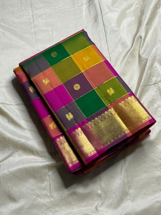 Pallavi – Kanchipuram Paalum pazhamum checks/ Zari kattam  Silk Saree in Turmeric, Mango, Leaf Green & Beetroot Pink Checks.
Finished with a vibrant magenta border and rich gold zari pallu.
