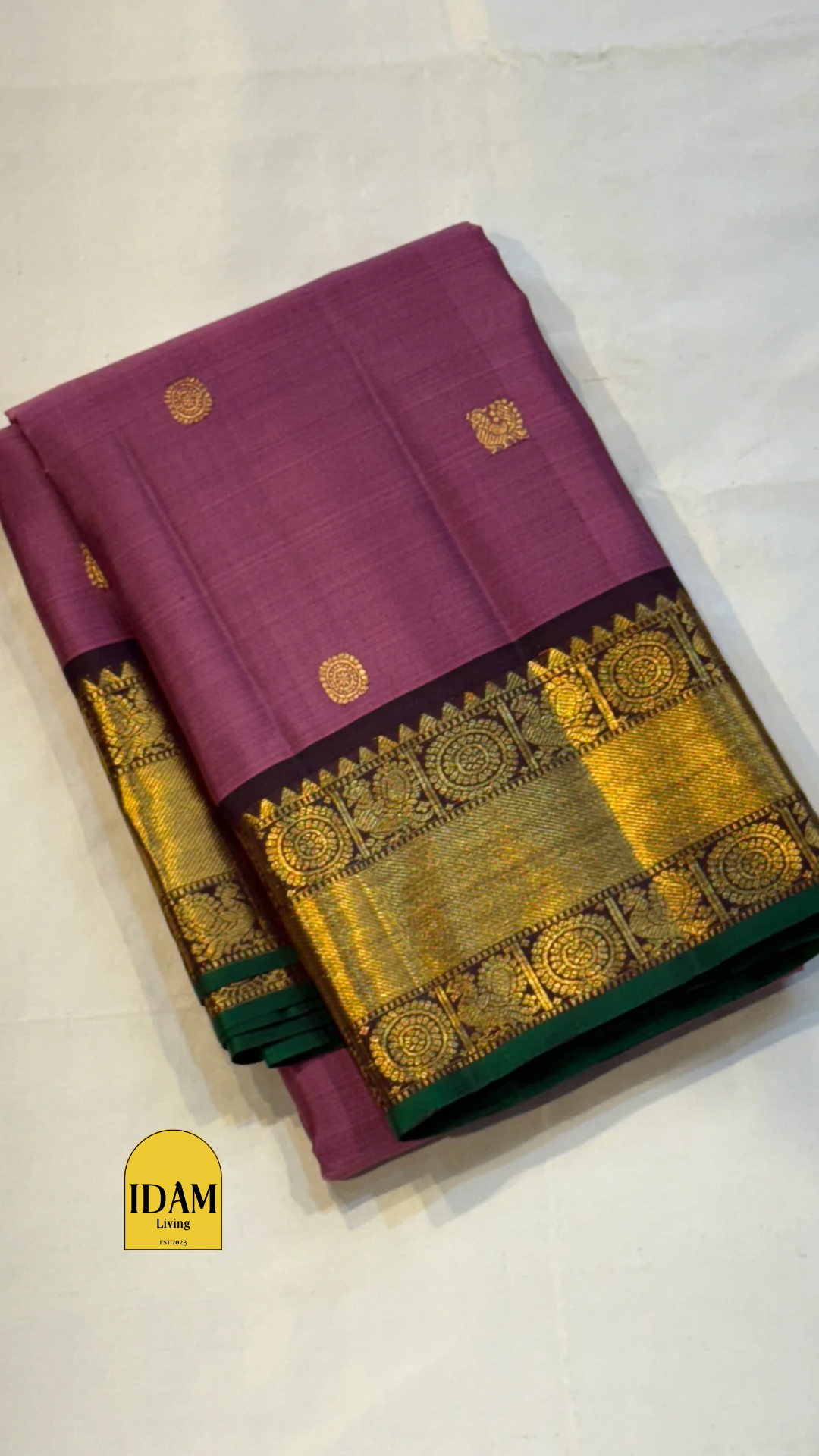 Tanaya features a regal mulberry mauve purple body adorned with golden kamalam and mayil buttas. Its elegant dual-tone border—coffee brown on top and emerald green below with rich temple-inspired zari work with medallions and florals woven, rich Pallu.