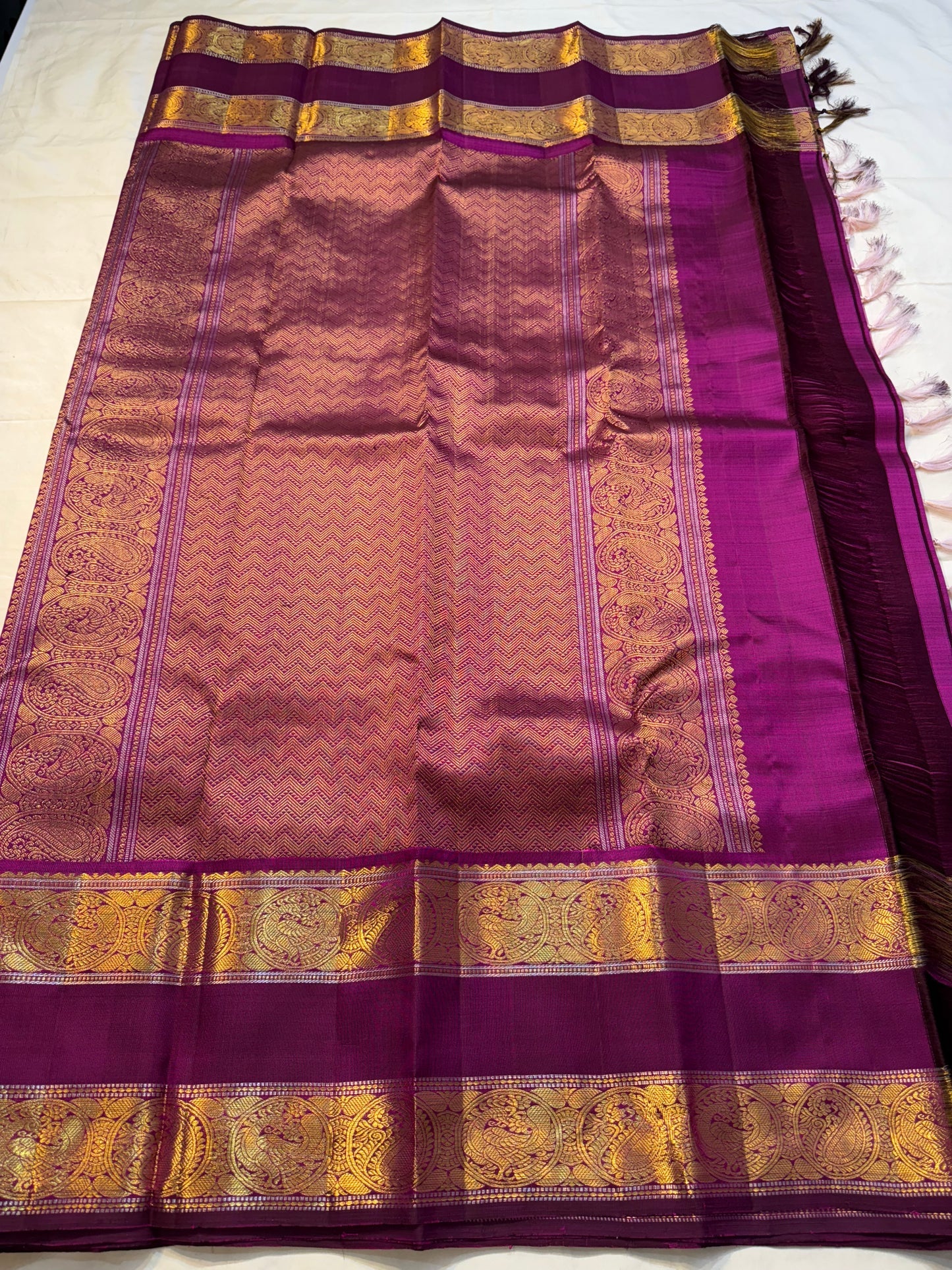 Mauve Mayil Mukham — Kanchipuram Pure Silk

Pastel-mauve pink  body with delicate zari wide kattam checks

Deep plum korvai border with grand mayil (peacock) chakram motifs

Copper-rose chevron zari pallu & plum contrast blouse

Silk Mark Certified • Free