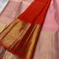 Rose Twilight — Kanchipuram Pure Silk

 Soft blush-pink (gulabi) body with gold floral buttas

Rosé-gold zari borders with floral vines & creepers

Vermilion-orange contrast pallu with kaddi & brocade panels

Silk Mark Certified | Free Shipping within USA