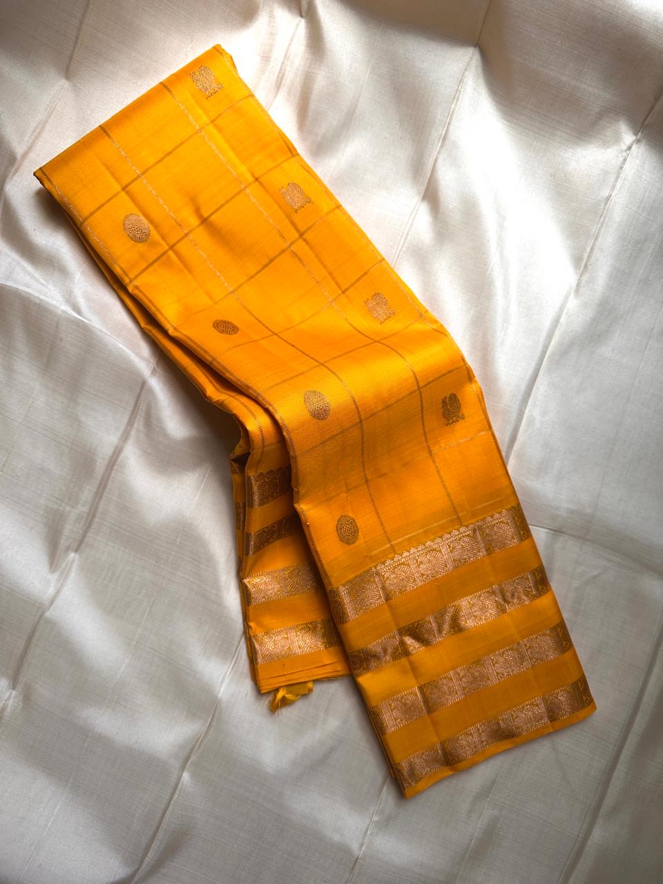 Kanaka – Sunlit Mustard Kanchipuram Silk Saree with Checked Zari Buttas and Gold Striped Border
A radiant weave that captures the warmth of tradition and the glow of celebration