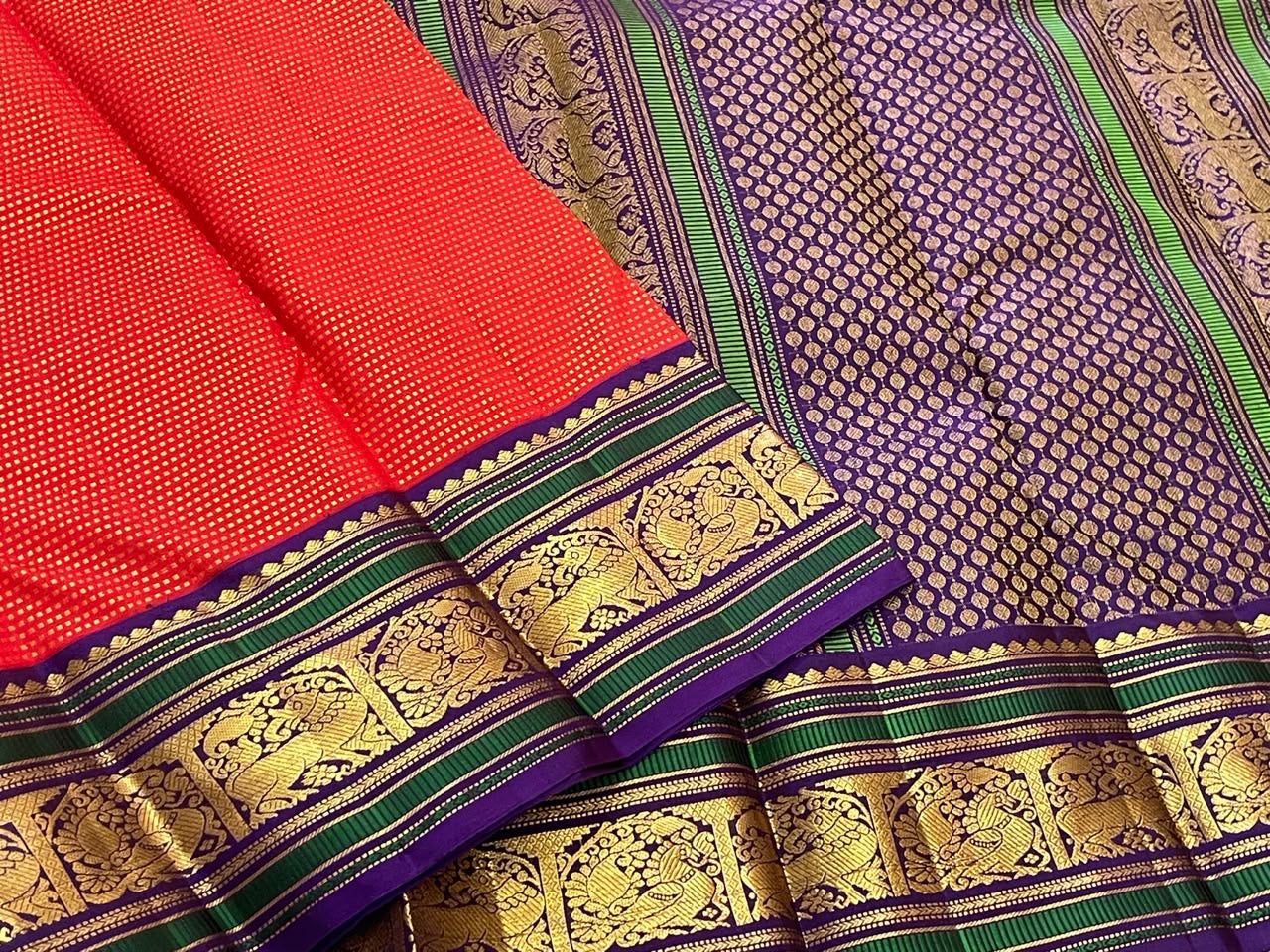 Handwoven Kancheepuram Butta saree in deep red with all-over dense gold zari butta and deep purple green Mayil Yazhi Butta border, full folded view